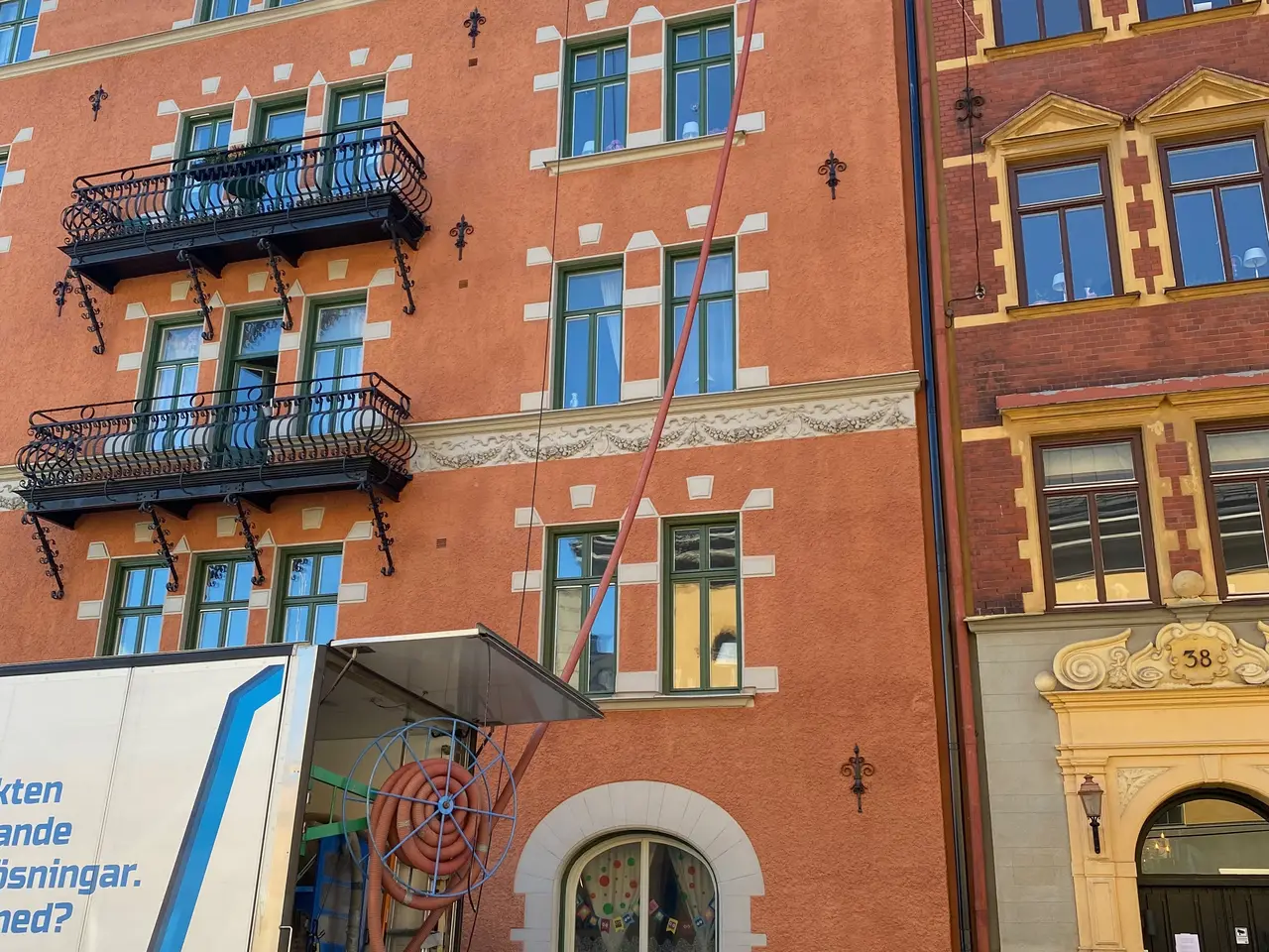 Flerbostadshus i tegel med lastbil vid trottoaren